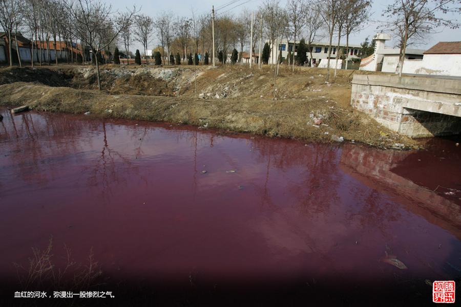 A river is tinted red by pollution near a village in Shenqiu, Henan Province