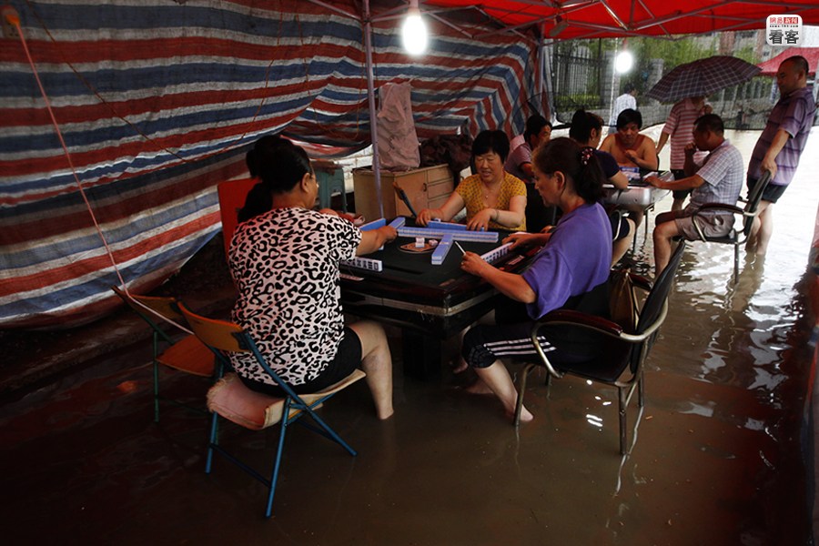 A group of Mahjong fans are playing Mahjong in a flooded Mahjong club. 