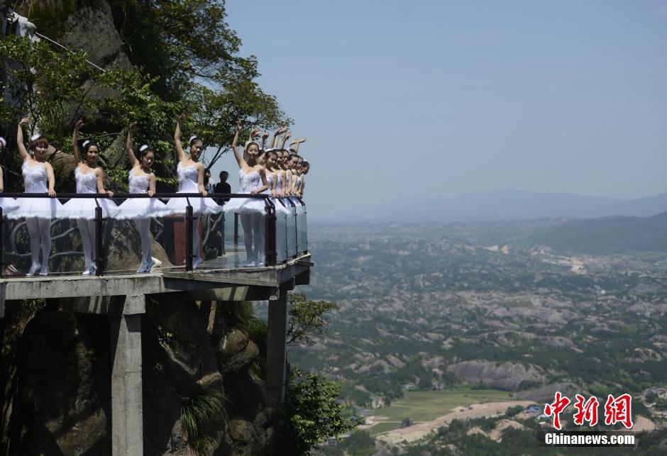 A group of ballet dancers pose on a crystal glass skywalk in Hunan